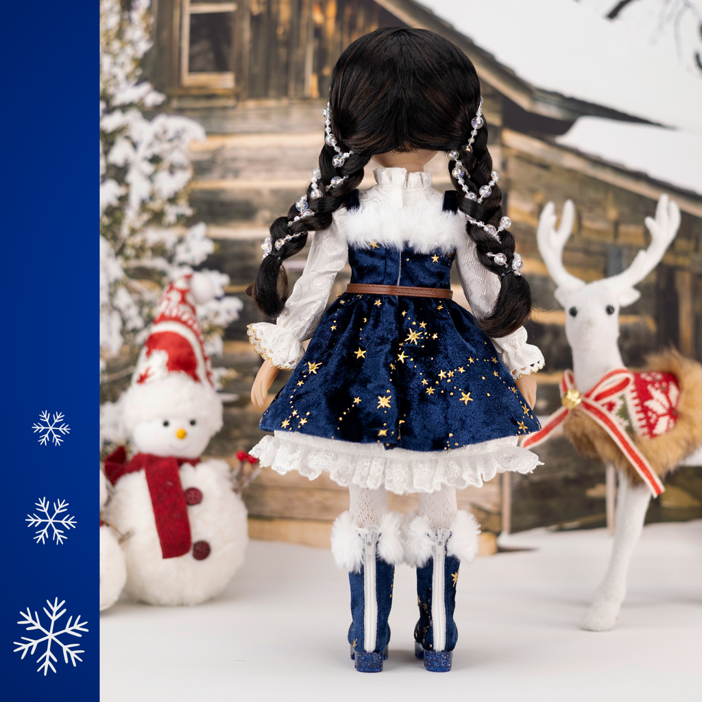 Ruby Red 2025 Holiday edition doll Carol, with festive blue and white outfit and accessories, surrounded by Christmas decorations.