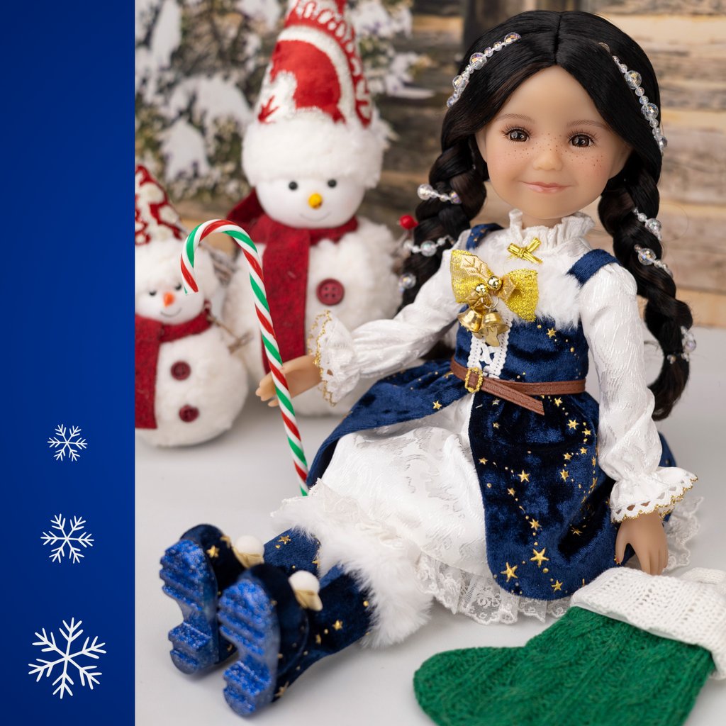 Ruby Red 2025 Holiday edition doll Carol, with festive blue and white outfit and accessories, surrounded by Christmas decorations.