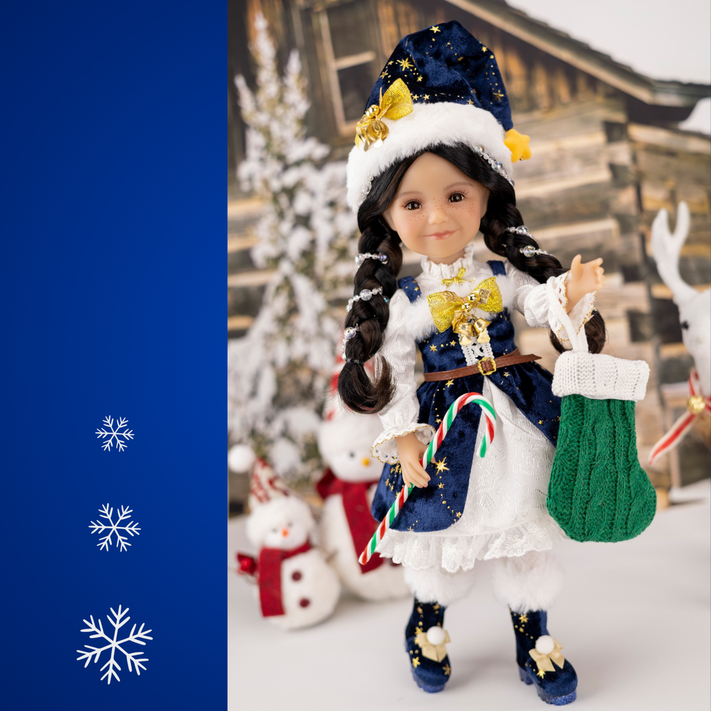 Ruby Red 2025 Holiday edition doll Carol, with festive blue and white outfit and accessories, surrounded by Christmas decorations.