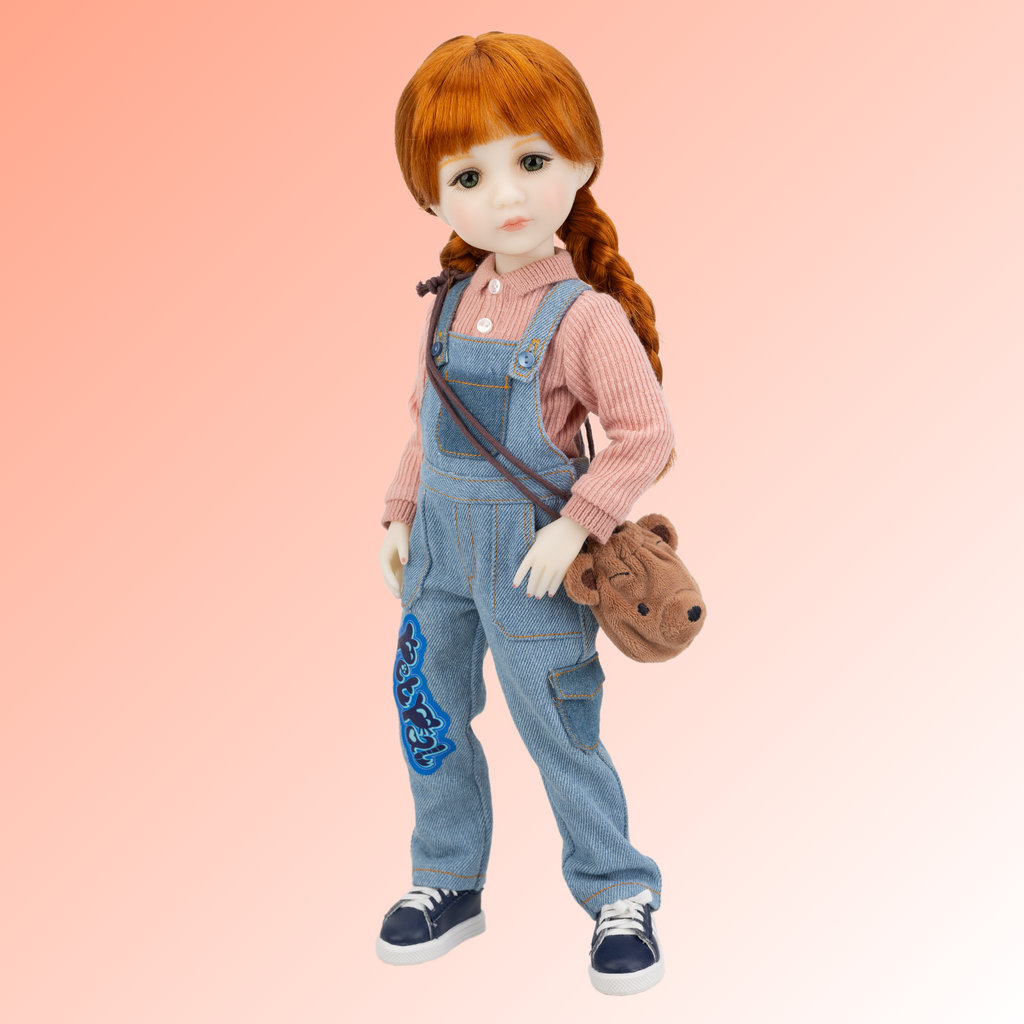 New ruby red core line doll Tina, wearing salmon coloured button up shirt and overalls with blue lace up sneakers and a teddy bear bag.